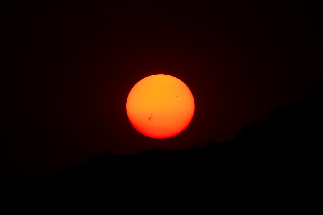 the sun is setting in the dark sky