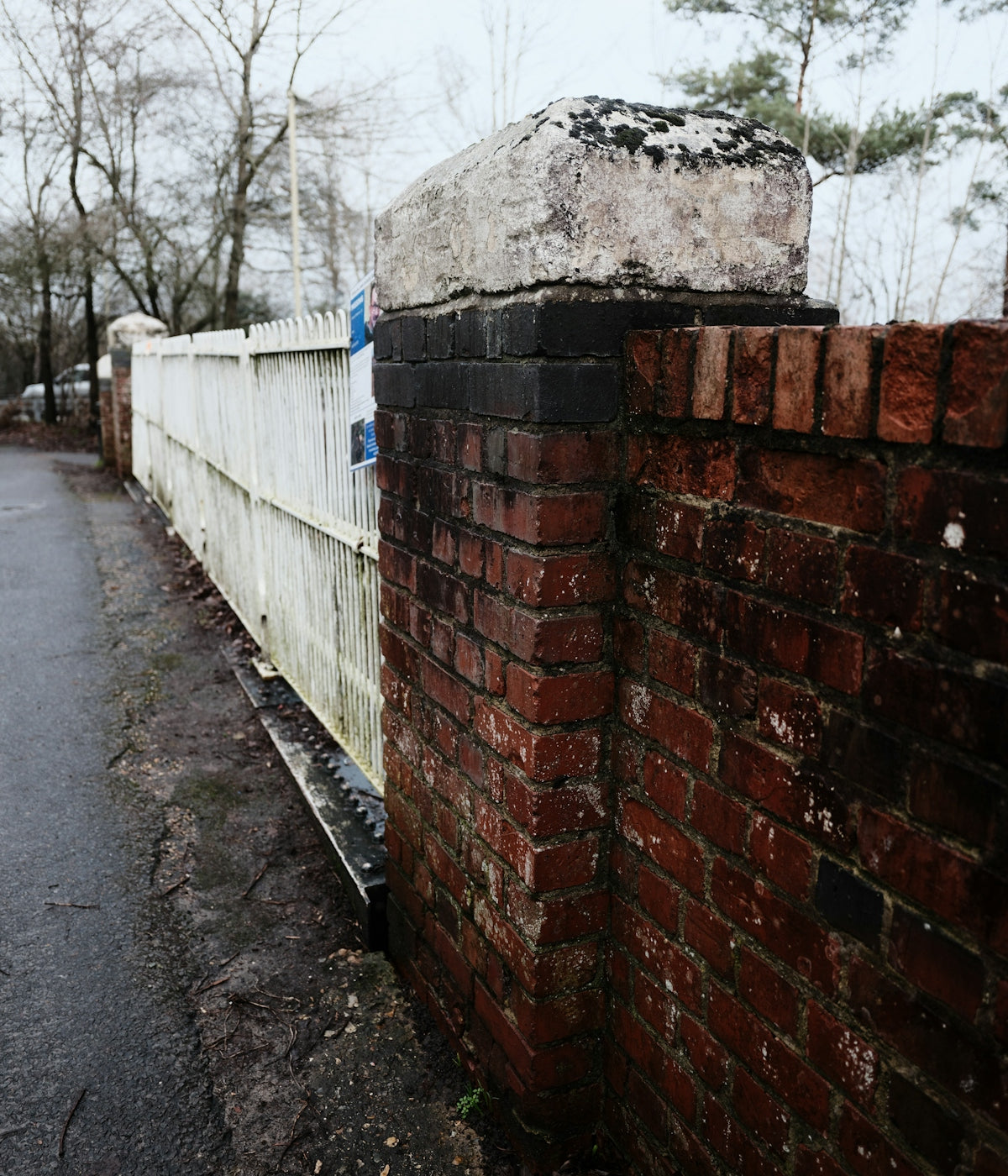 Brick and white picket fence with trees
